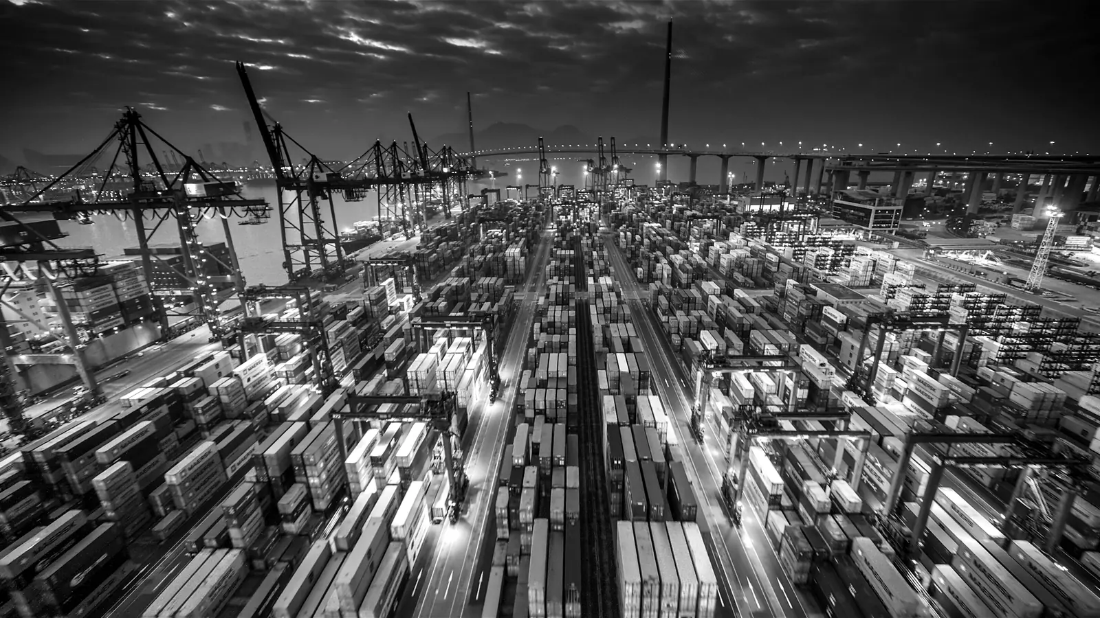 Terminal de contenedores de noche con grúas pórtico, en blanco y negro